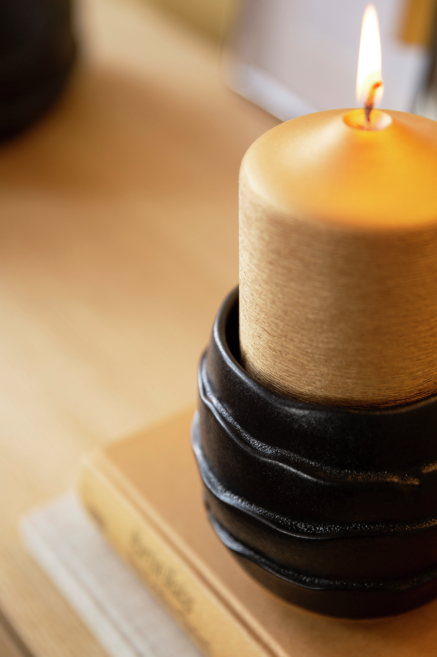 Nahaufnahme eines brennenden Windlichts aus Keramik mit Glas, das auf einem Buch steht.