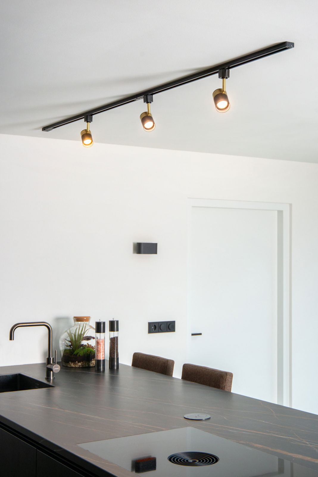 Deckenstrahler FLORIS in Schwarz mit drei verstellbaren Leuchten, montiert über einer modernen Kücheninsel, seitliche Perspektive