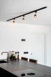 Deckenstrahler FLORIS in Schwarz mit drei verstellbaren Leuchten, montiert über einer modernen Kücheninsel, seitliche Perspektive