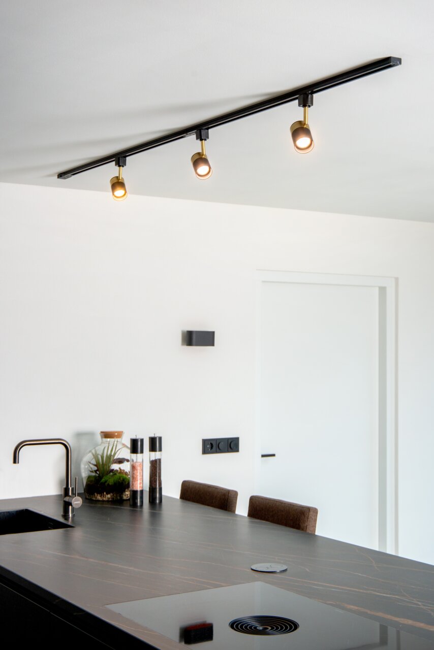 Deckenstrahler FLORIS in Schwarz mit drei verstellbaren Leuchten, montiert über einer modernen Kücheninsel, seitliche Perspektive