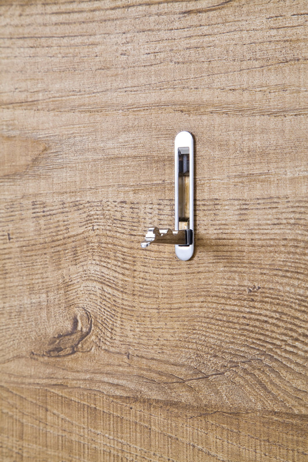 Nahaufnahme eines Holzschranks mit einem silbernen, ausklappbaren Haken in der Mitte.