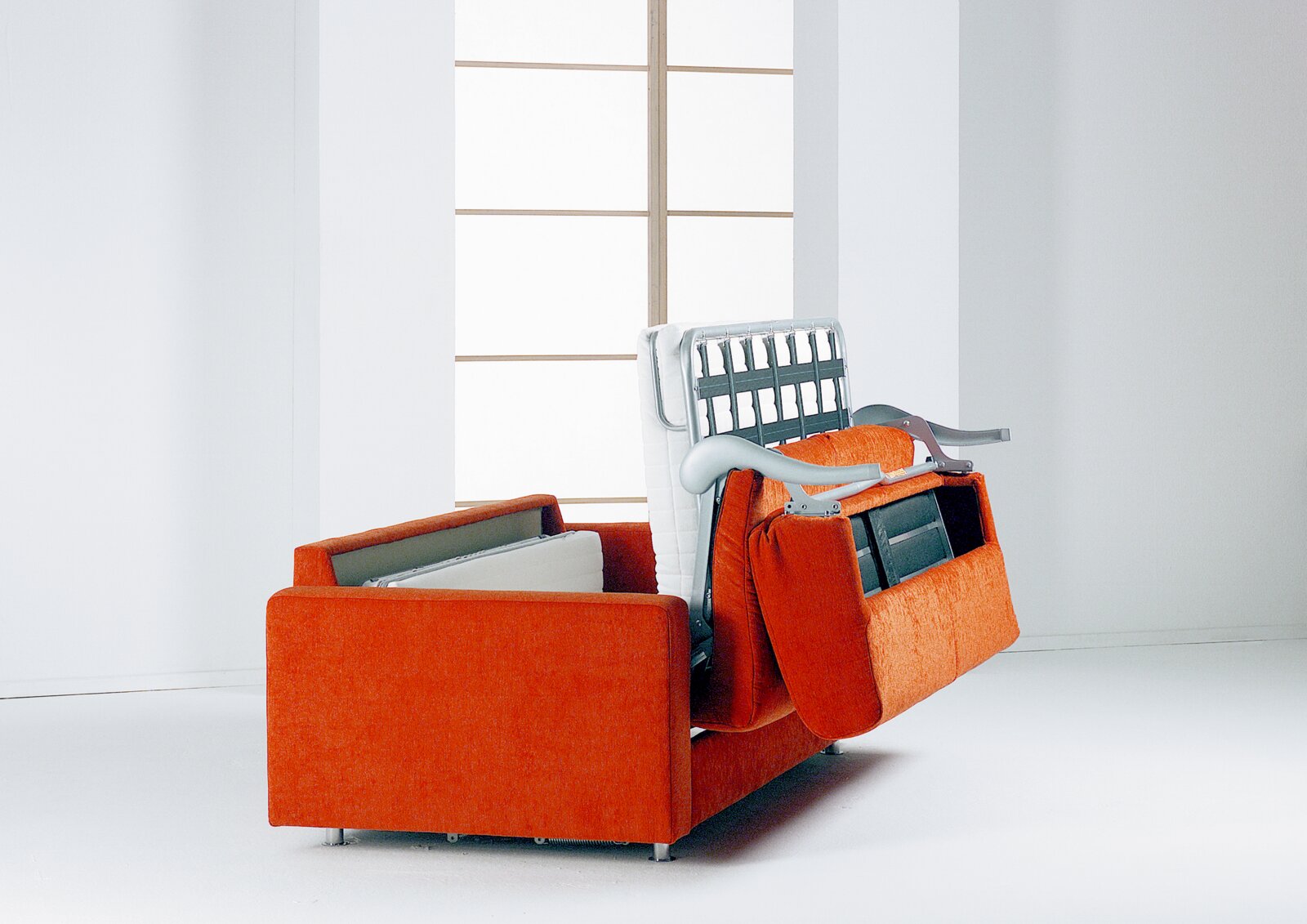 Orangefarbenes Schlafsofa mit ausgeklappter Bettmechanik, schräg von vorne in einem hellen Wohnraum gezeigt
