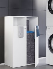 Weißer Wäscheschrank/Wäschekipper mit zwei Frontklappen und Textil-Wäschesack, in moderner Waschküche neben Waschmaschine, Perspektive: leicht schräg von vorne