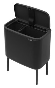 Schwarzer Abfalleimer mit geöffnetem Deckel, auf vier Beinen stehend, aus einer leicht erhöhten Perspektive fotografiert.