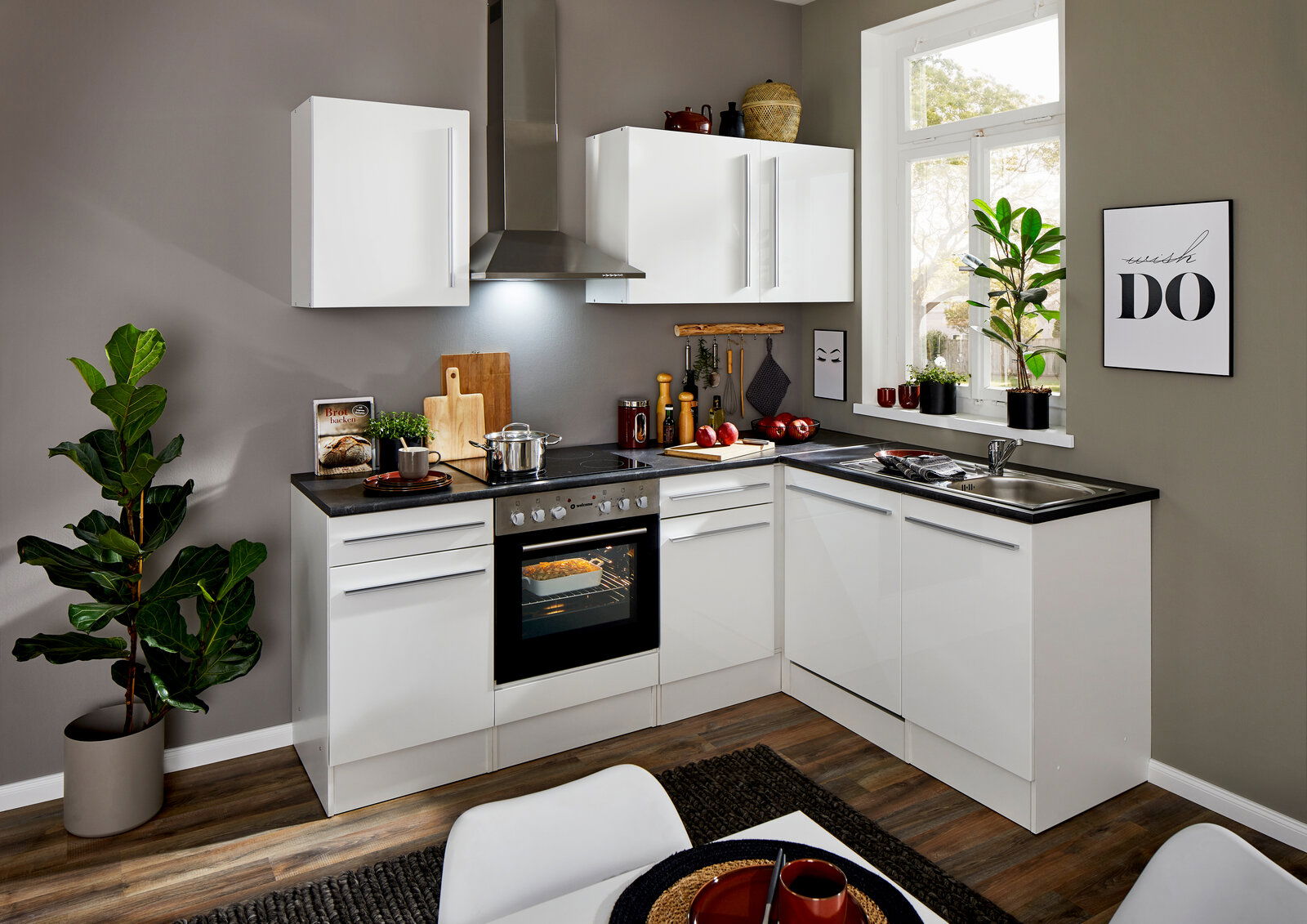 Moderne weiße Eckküche mit Eckunterschrank, Herd und Spüle, aus der Perspektive eines Betrachters im Raum.