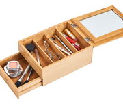 Offenes Schmuckkästchen aus Holz mit Spiegel, gefüllt mit Kosmetikartikeln, aus der Vogelperspektive.