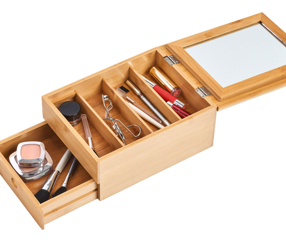 Offenes Schmuckkästchen aus Holz mit Spiegel, gefüllt mit Kosmetikartikeln, aus der Vogelperspektive.