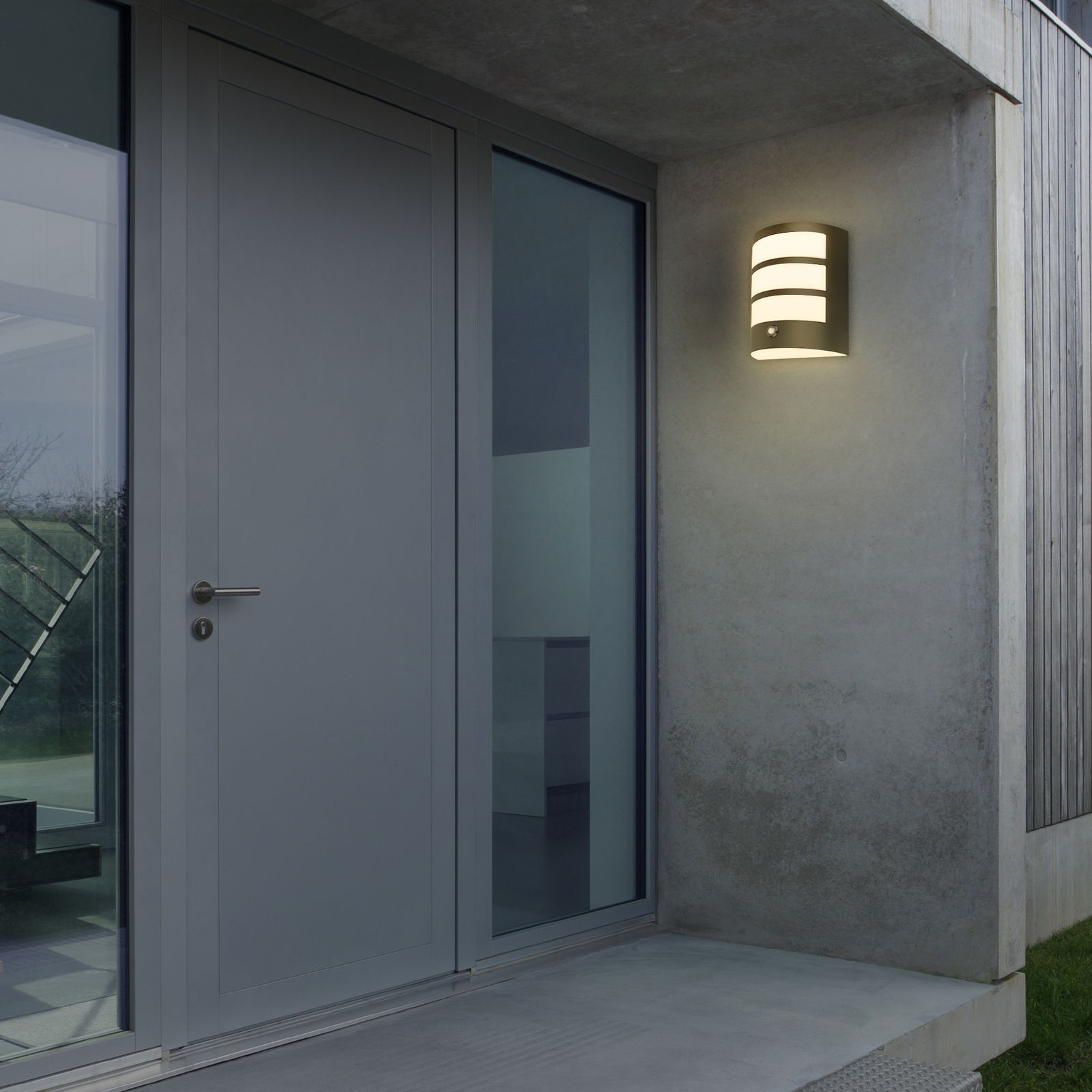 Moderne Akku-Außenwandleuchte an einer Hauswand neben einer Tür, aus seitlicher Perspektive fotografiert.