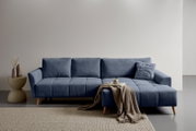 Modernes blaues Ecksofa mit Chaise longue rechts, gestepptem Stoffbezug und Holzfüßen, frontal aus leicht schräger Perspektive fotografiert; dekoriert mit Kissen, Decke und Tablett im minimalistischen Wohnraum.