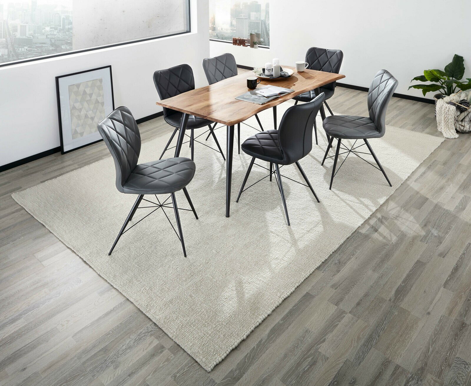 Moderner Esstisch mit Holzplatte und schwarzen Stühlen in einem hellen Raum, von oben betrachtet.