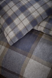 Nahaufnahme von kariertem Bettwäsche-Set in Blau- und Brauntönen, Perspektive von oben.