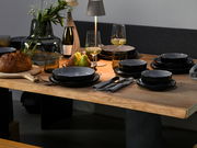 Elegantes Kombiservice 30-tlg. Frost auf einem gedeckten Tisch, seitliche Perspektive, mit modernen schwarzen Tellern und Schalen, umgeben von stilvollen Gläsern, Besteck und Dekoration.