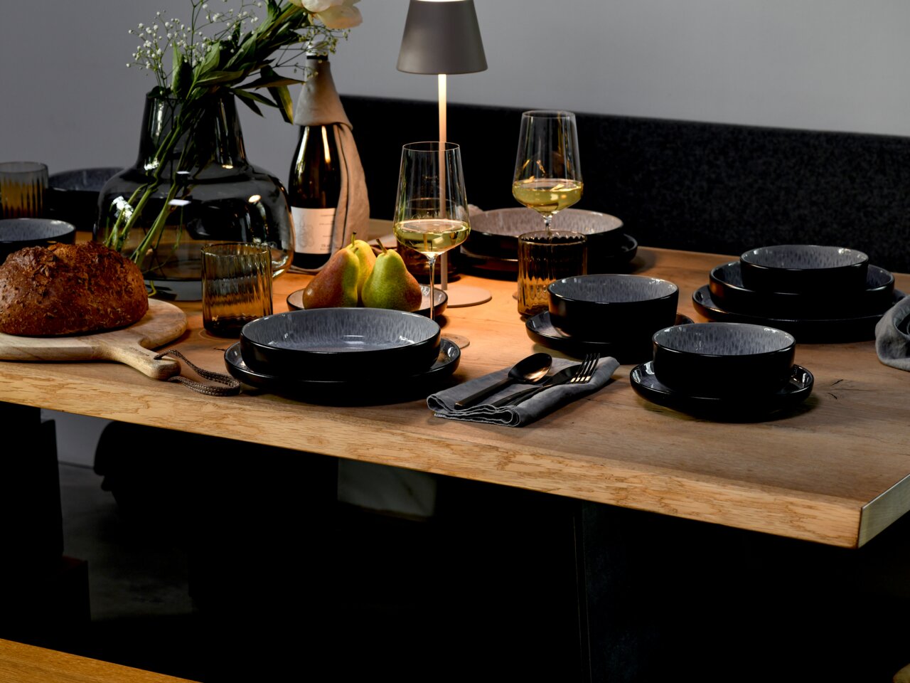 creaTable Kombiservice 30-tlg. Frost NORDIC FJORD Elegantes Kombiservice 30-tlg. Frost auf einem gedeckten Tisch, seitliche Perspektive, mit modernen schwarzen Tellern und Schalen, umgeben von stilvollen Gläsern, Besteck und Dekoration.
