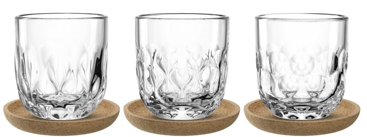 Drei elegante, klare Kaffeegläser mit dekorativem Muster, präsentiert auf runden Untersetzern, Frontalansicht.