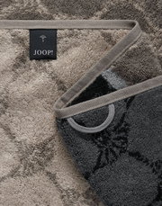Nahaufnahme eines luxuriösen Duschtuchs mit elegantem Muster und JOOP!-Label, in einer diagonalen Perspektive.