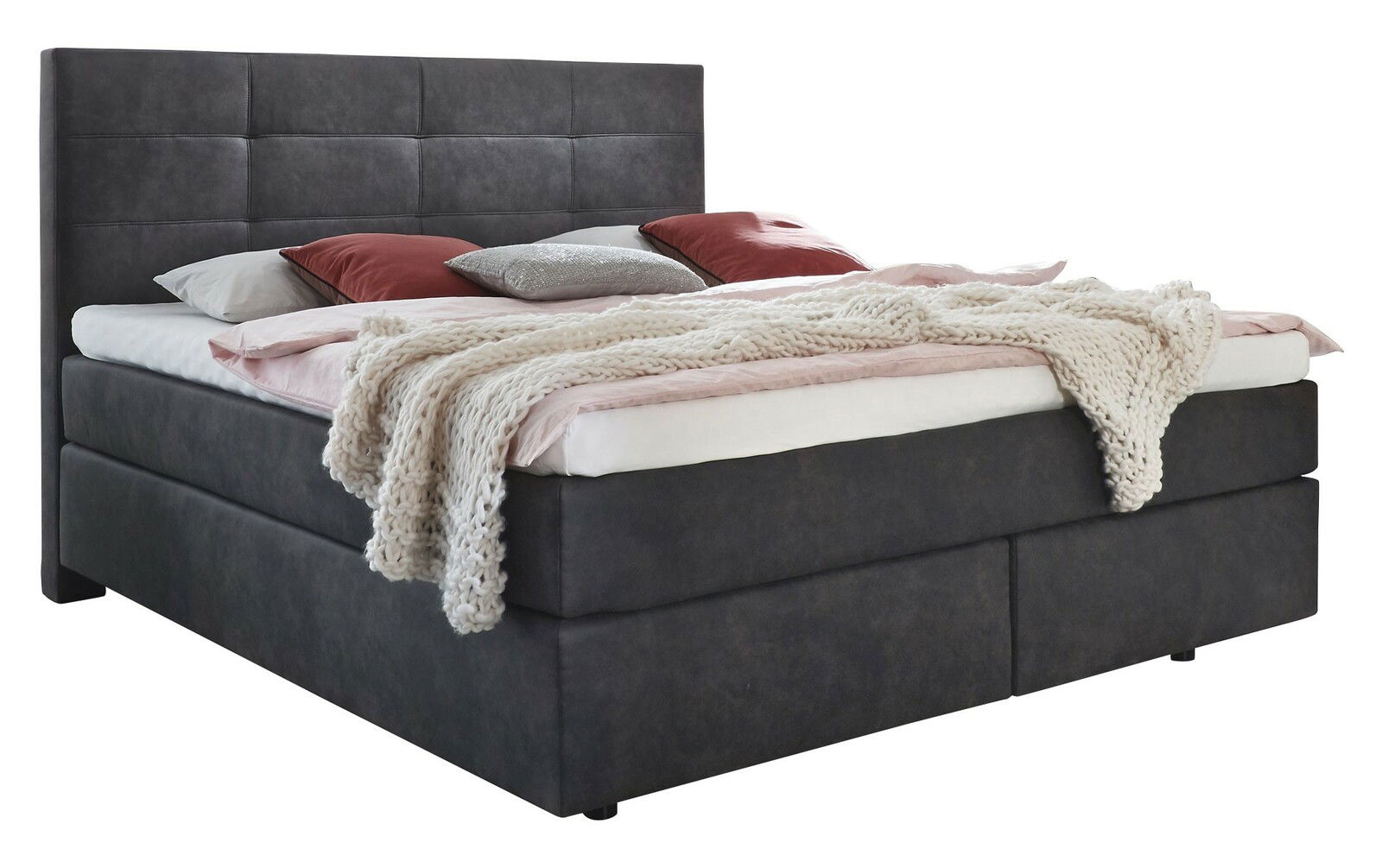 Boxspringbett in dunklem Stoffbezug mit hohem Kopfteil, dekoriert mit Kissen und einer gestrickten Decke, seitliche Perspektive