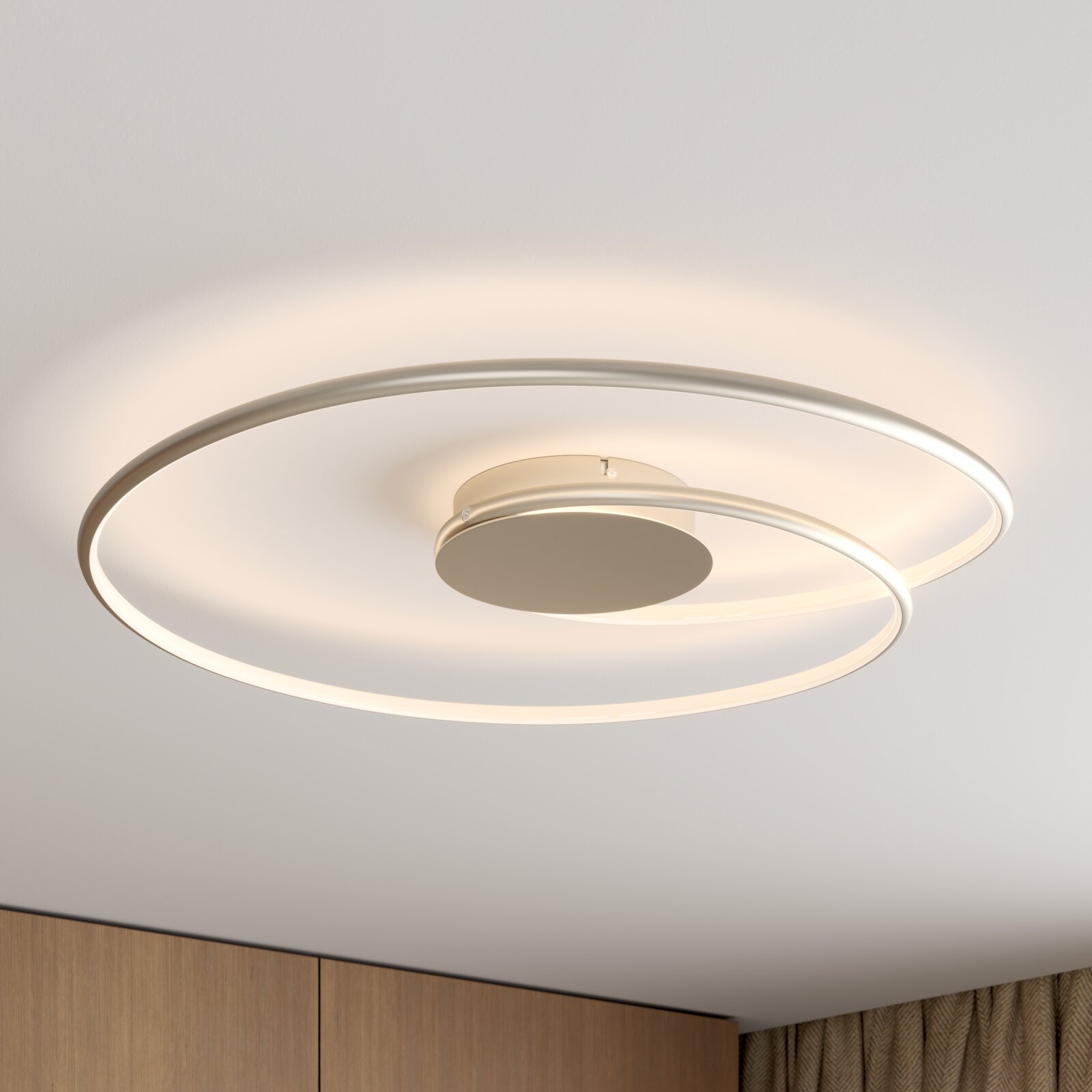 Moderne LED-Deckenleuchte in Ringform mit zwei überlappenden Lichtkreisen in Weiß, warmweiß leuchtend, montiert an der Zimmerdecke; Perspektive von unten schräg nach oben