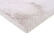 Nahaufnahme eines weichen, flauschigen Fellteppichs in hellem Beige, von der Seite fotografiert.