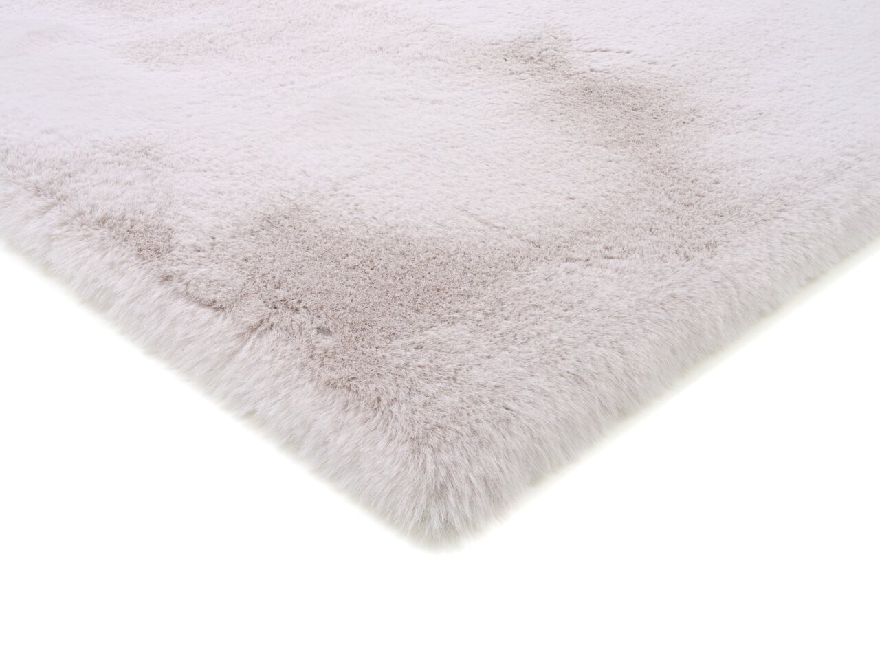 Nahaufnahme eines weichen, flauschigen Fellteppichs in hellem Beige, von der Seite fotografiert.
