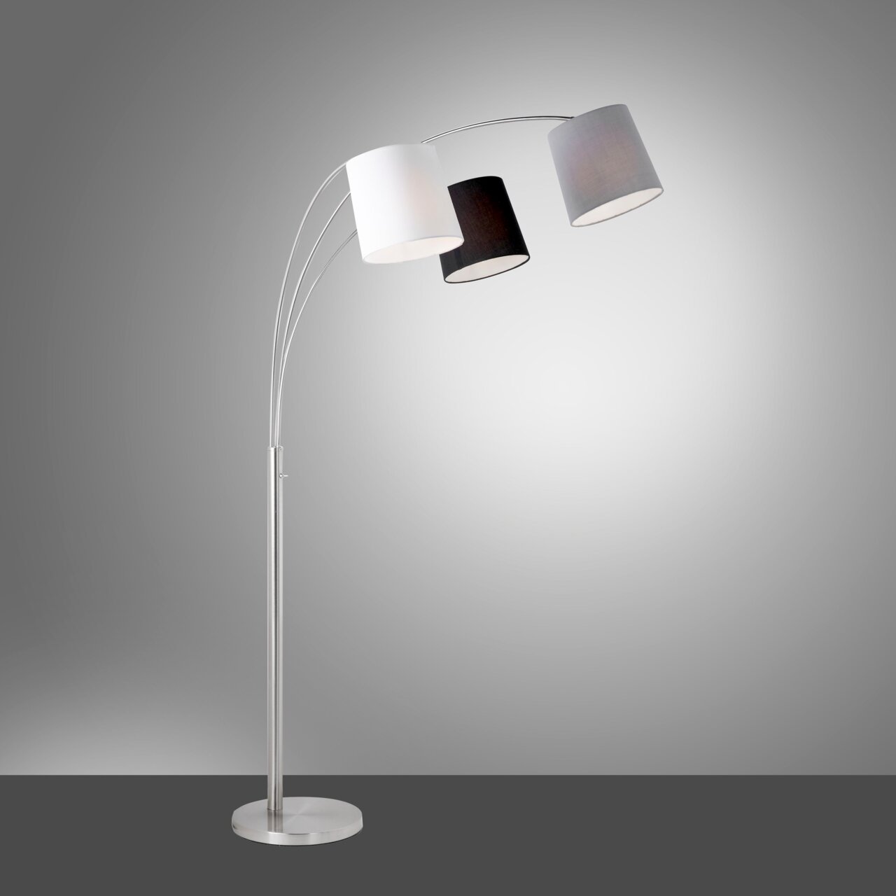 Moderne Stehleuchte aus Stahl mit drei gebogenen Armen und unterschiedlich farbigen Lampenschirmen in Weiß, Schwarz und Grau, seitliche Perspektive.