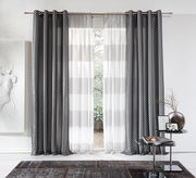 Grauer Ösenvorhang von Stöckel & Grimmler, Modell JOOP, in einem modernen Wohnzimmer. Der Vorhang hat ein elegantes Muster und hängt an einer Metallstange. Die Perspektive zeigt den Vorhang frontal mit einem Blick nach draußen durch das Fenster.