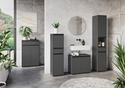 Moderne Badezimmermöbel in dunklem Grau, bestehend aus einem hohen Schrank, einem Waschbeckenunterschrank und einem weiteren Schrank, in einer stilvollen Badezimmerumgebung mit Pflanzen und einem runden Spiegel. Frontalansicht.