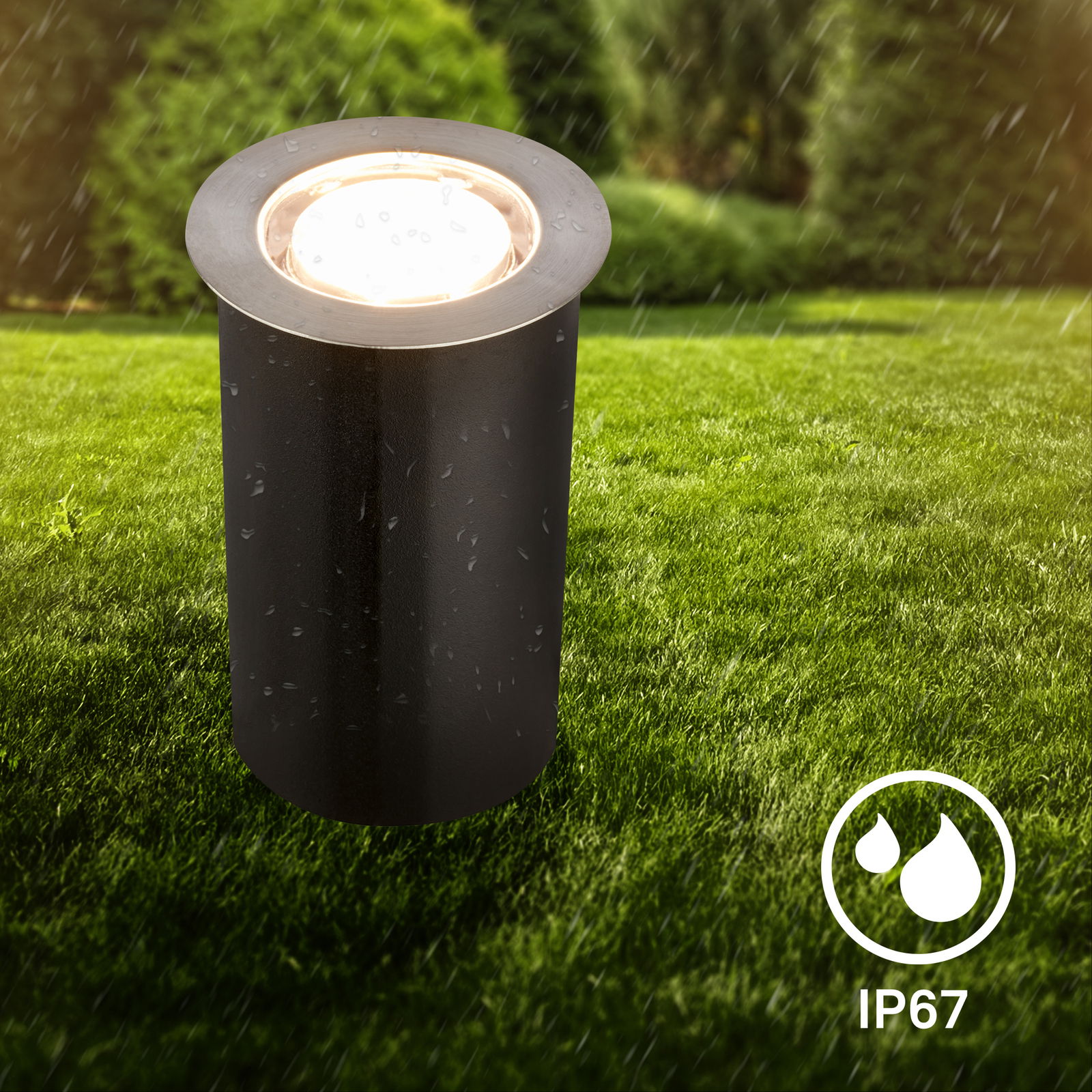 Edelstahl-Bodenleuchte im Freien, zylindrische Form, bei Regen auf einer Rasenfläche, IP67 wasserdicht, seitliche Perspektive