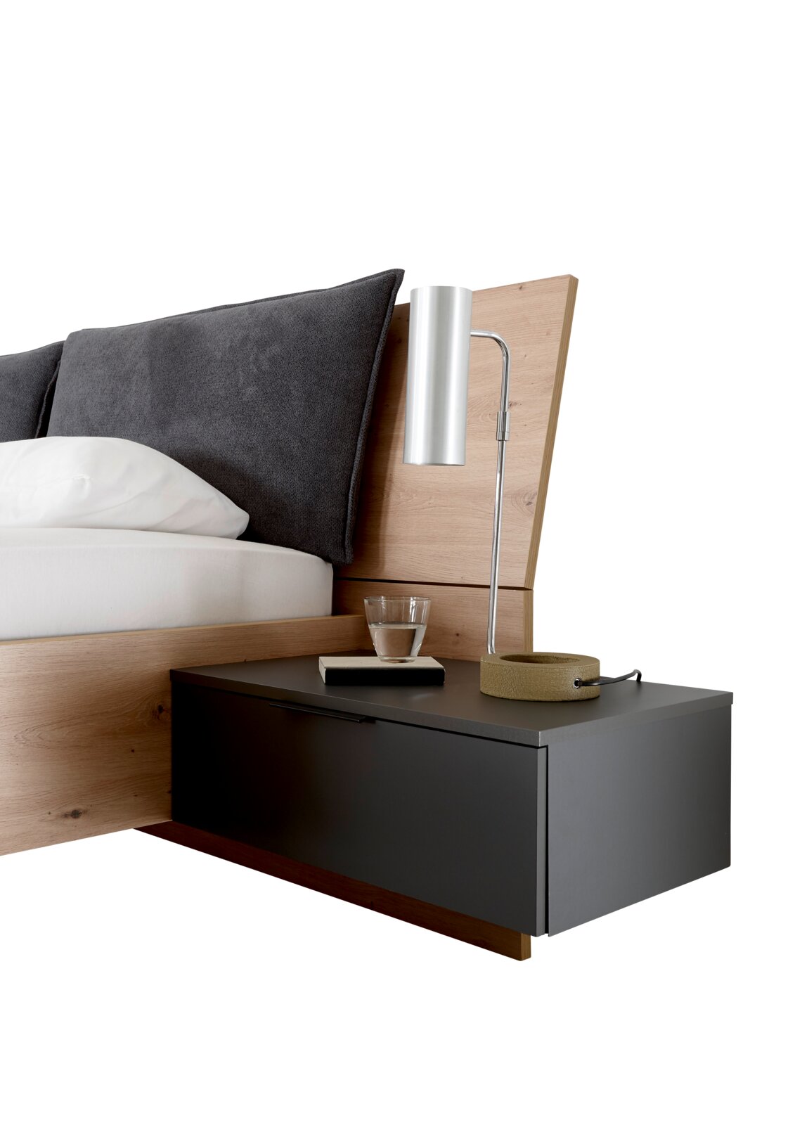 Close-up van een modern bed met hout- en grijstinten, inclusief hoofdeinde, kussens, nachtkastje en lamp, gezien vanaf de zijkant.