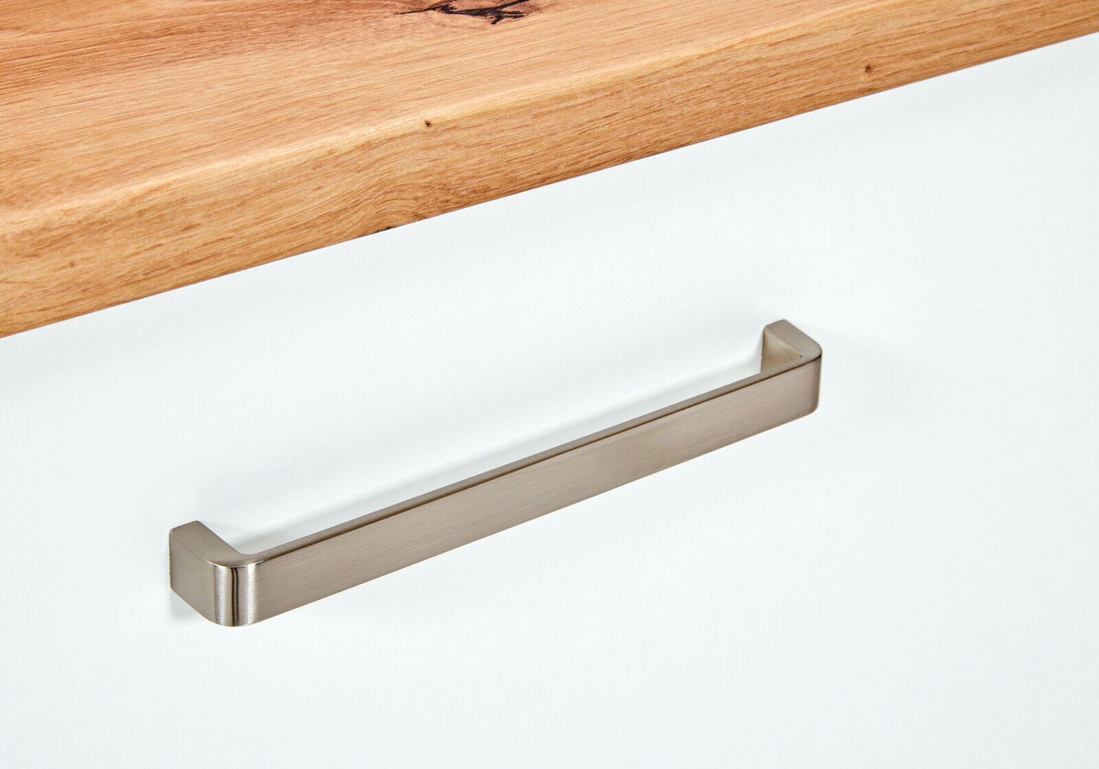 Nahaufnahme eines Spülenunterschranks mit einer Holzarbeitsplatte und einem modernen, silbernen Griff.