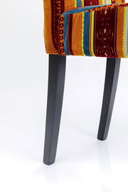 Nahaufnahme eines Stuhls mit buntem, gestreiftem Stoffbezug und schwarzen Beinen, seitliche Perspektive.