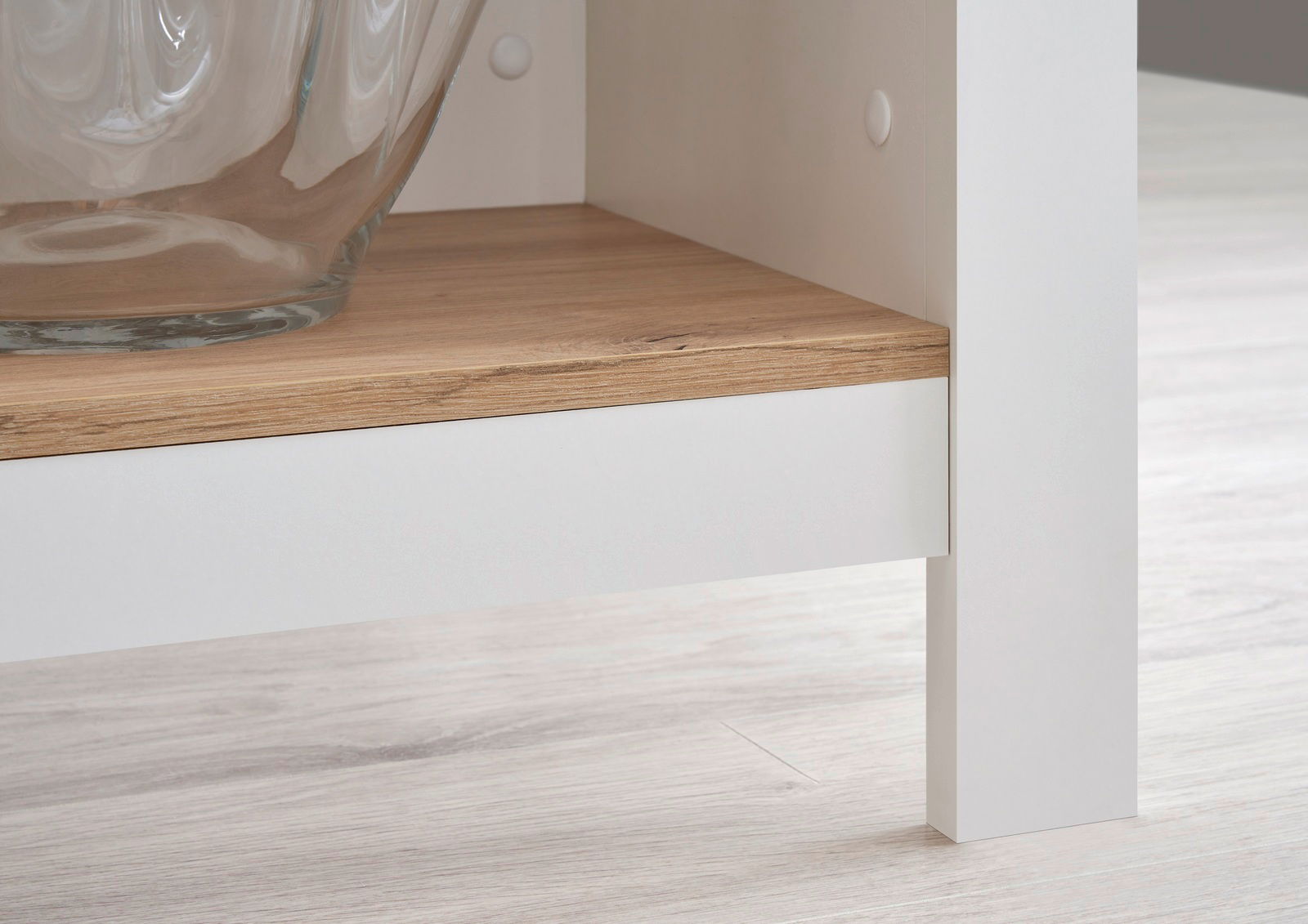 Detailansicht einer Kücheninsel mit weißem Rahmen und Holzablage, perspektivisch von der Seite aufgenommen.