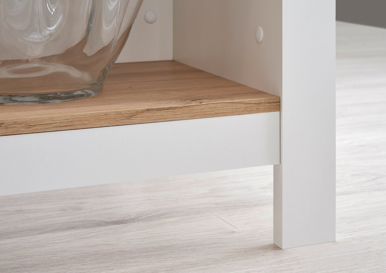 Detailansicht einer Kücheninsel mit weißem Rahmen und Holzablage, perspektivisch von der Seite aufgenommen.