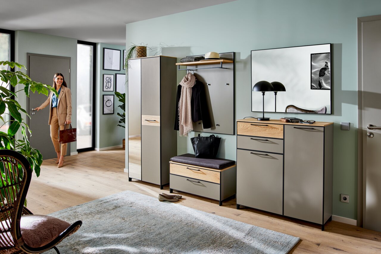 Moderne Garderobeneinrichtung mit Schuhschrank, Garderobenbank, Spiegel und Paneel in einem hellen Flur. Perspektive von vorne.