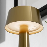 Close-up van een moderne staande lamp van geborsteld messing met een warm verlicht, gestructureerd diffusoroppervlak, gefotografeerd vanuit een onderaanzicht (van onderaf)