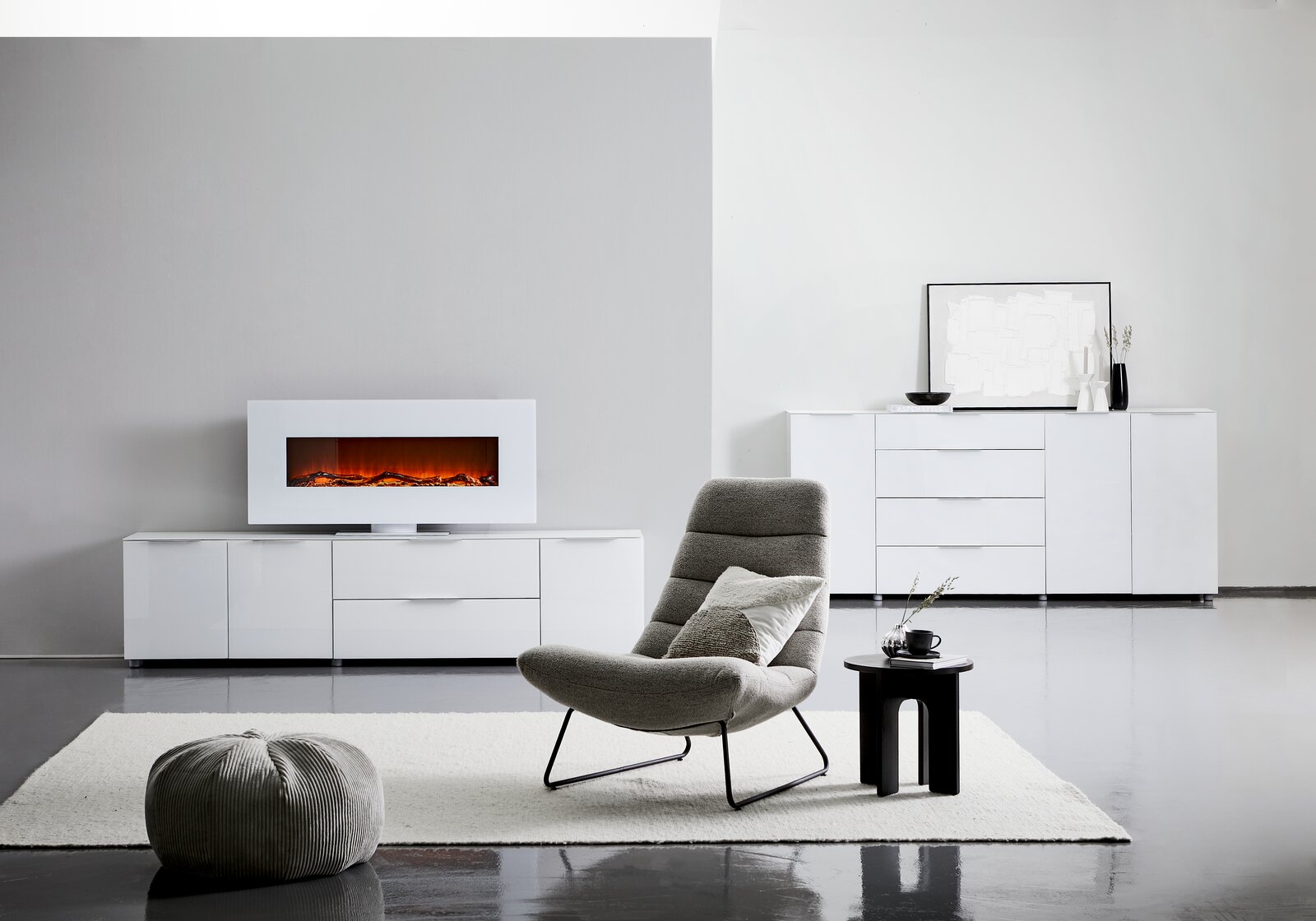 Modernes XL-Sideboard in Weiß mit Hochglanzoberfläche, zentral im Raum platziert, mit dekorativem Elektrokamin auf der linken Seite und stilvollen Accessoires auf der rechten Seite.