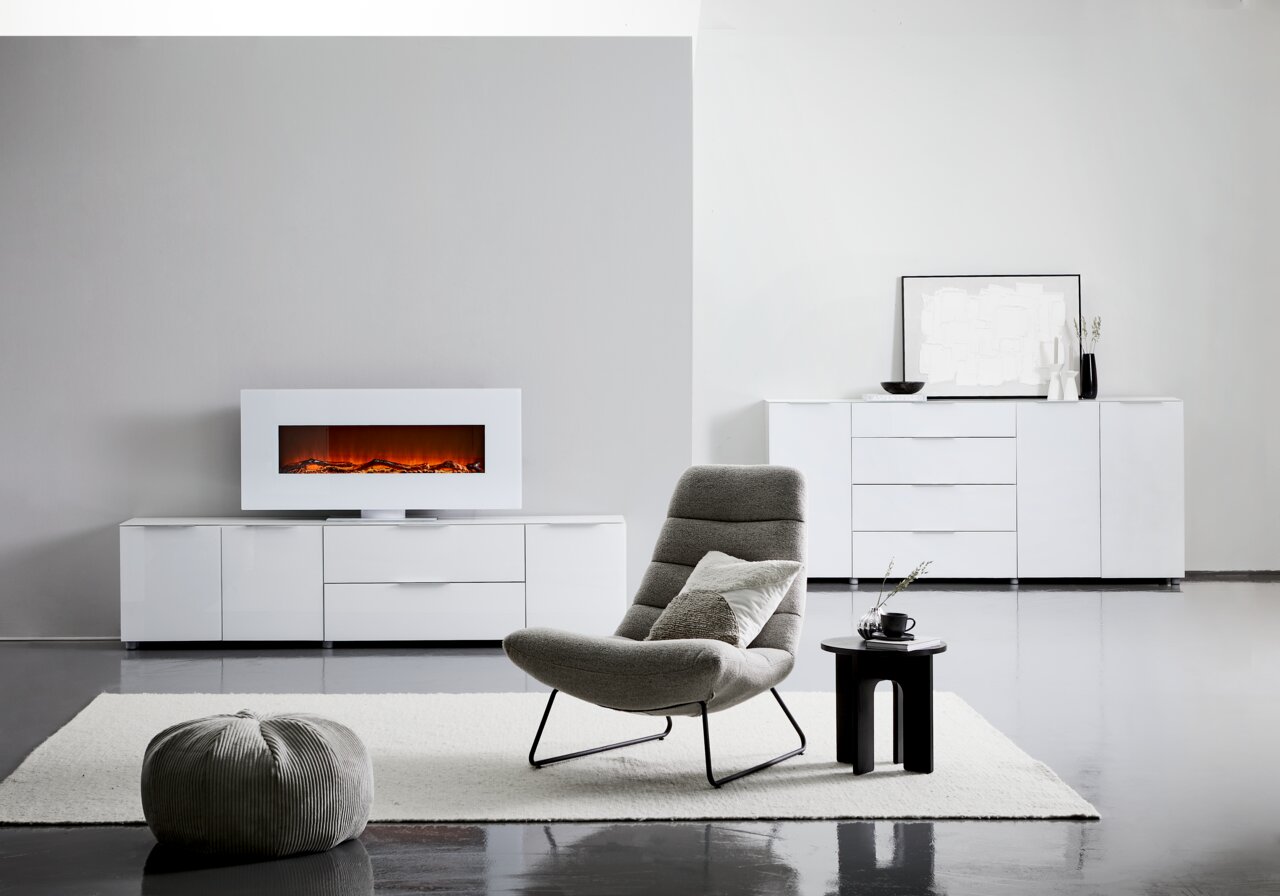 Modernes XL-Sideboard in Weiß mit Hochglanzoberfläche, zentral im Raum platziert, mit dekorativem Elektrokamin auf der linken Seite und stilvollen Accessoires auf der rechten Seite.