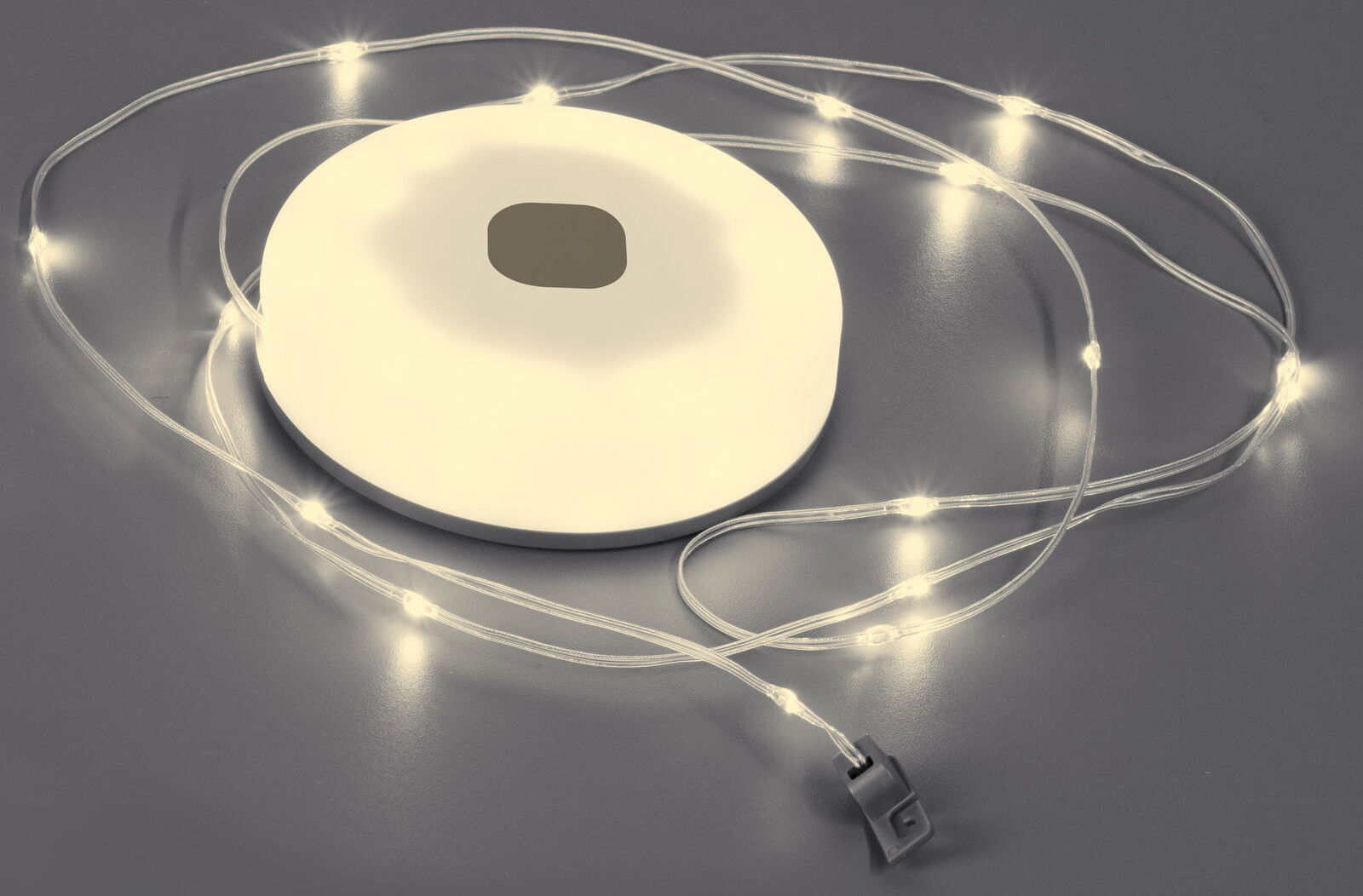 FHL easy LED-Lichterkette BENNI LED-Lichterkette BENNI 10m, Draufsicht auf eine weiße Basis mit leuchtenden Lichtern auf grauem Hintergrund