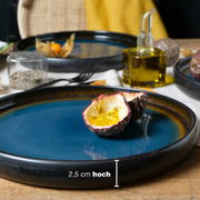 Blau-brauner Dinner Teller mit einer Höhe von 2,5 cm, darauf eine halbierte Passionsfrucht, seitliche Perspektive.