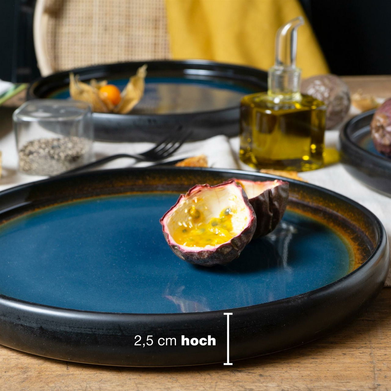 Blau-brauner Dinner Teller mit einer Höhe von 2,5 cm, darauf eine halbierte Passionsfrucht, seitliche Perspektive.