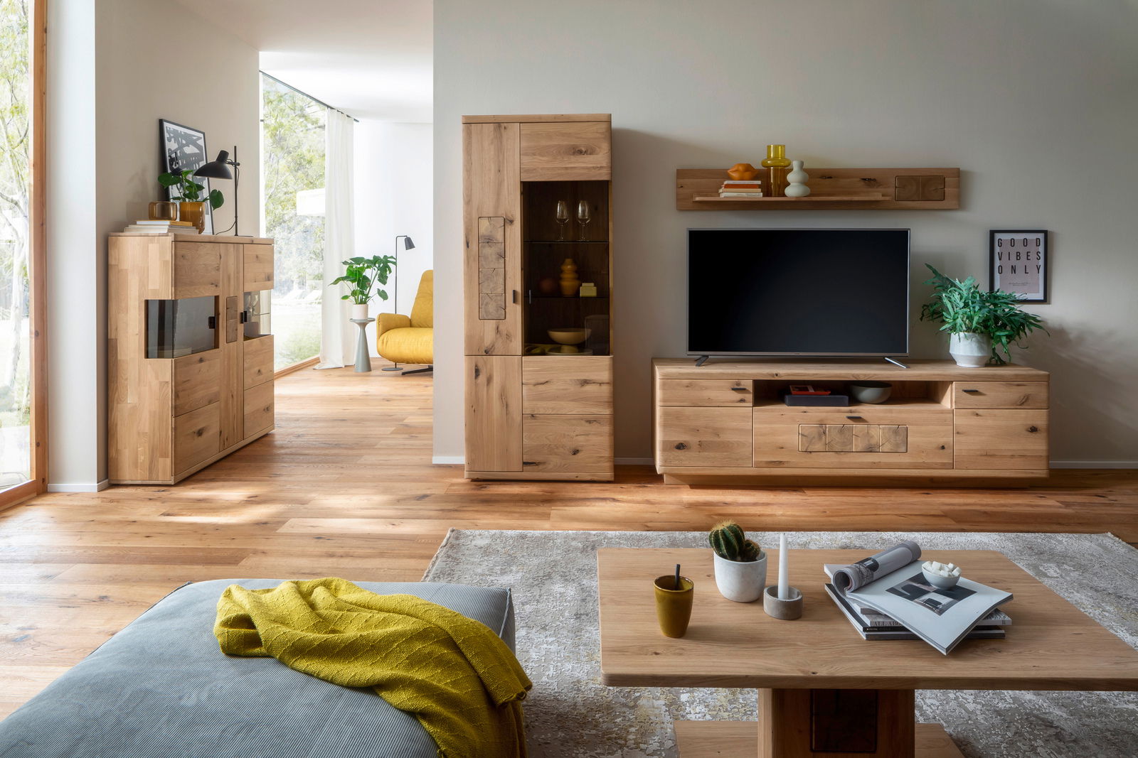 Wohnzimmer mit moderner Holzmöbelkombination, bestehend aus Highboard, TV-Board und Wandregal, aus hellem Holz. Perspektive von vorne.