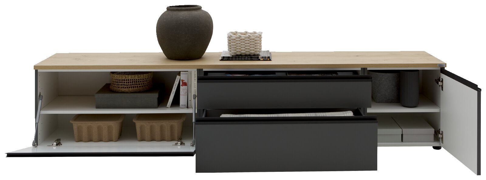 Modernes Lowboard/TV-Board mit heller Holzplatte und dunklen Fronten, links und rechts mit geöffneten Klapptüren und mittig zwei ausgezogenen Schubladen, gefüllt mit Deko und Aufbewahrung, in frontaler Ansicht.