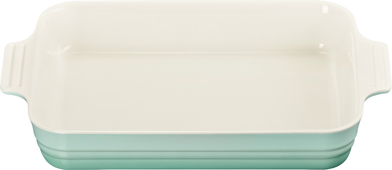 Rechteckige Auflaufform aus Keramik in Cremeweiß mit helltürkisem Unterteil und seitlichen Griffen, Ansicht von oben leicht frontal vor weißem Hintergrund