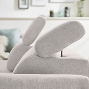 Nahaufnahme eines hellgrauen Ecksofas mit verstellbarer Kopfstütze, seitliche Perspektive.