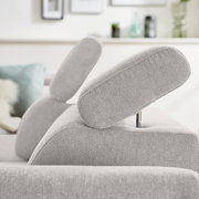 Nahaufnahme eines hellgrauen Ecksofas mit verstellbarer Kopfstütze, seitliche Perspektive.