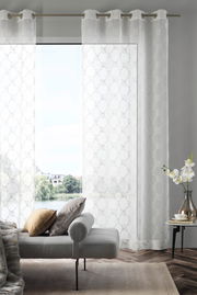 Ösenvorhang J!Airy natur in einem modernen Wohnzimmer, frontal betrachtet, mit einem Sofa und einem Beistelltisch im Vordergrund.