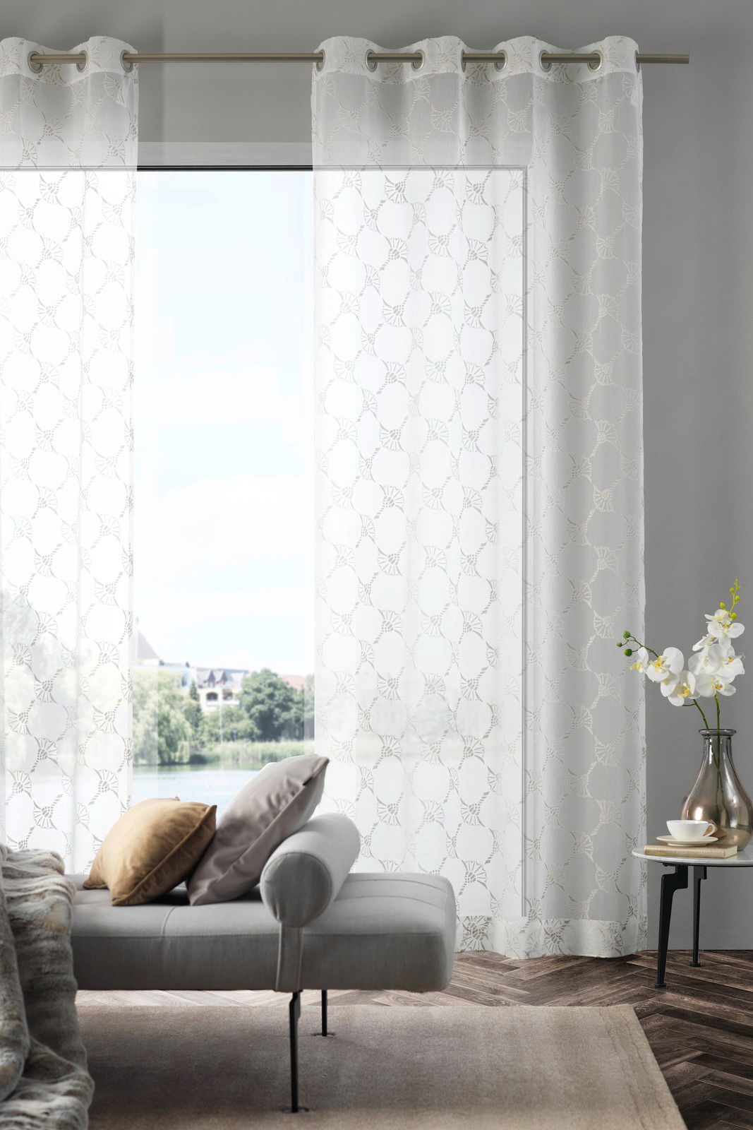 Ösenvorhang J!Airy natur in einem modernen Wohnzimmer, frontal betrachtet, mit einem Sofa und einem Beistelltisch im Vordergrund.