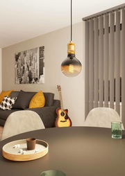 Pendelleuchte YORTH in einem modernen Wohnzimmer, aus der Perspektive über einem Tisch hängend, mit einer Glühbirne und goldener Fassung.