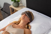 Frau liegt entspannt auf einem Bett und trägt eine Tempur Schlafmaske, seitliche Perspektive