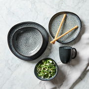 Kombiservice 10-tlg. in eleganter Steinoptik, bestehend aus Tellern, Schalen und einer Tasse, von oben fotografiert auf einem Marmortisch.