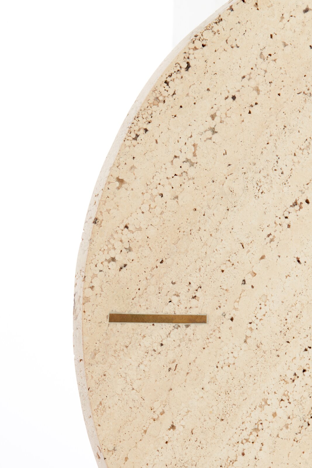 Close-up van een ronde klok van licht, gespikkeld steenmateriaal met een minimalistisch ontwerp, gezien vanaf de zijkant.